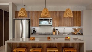 Une cuisine moderne dotée d’un îlot central, de touches de bois et de luminaires suspendus en osier.