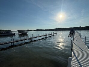 A calm lake with a wooden dock extending into the water, surrounded by hills. - Spacious 4BR Accessible Lake House w/ Dock Access, Pontoon & Hosting Spaces (Fremont)