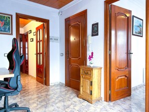 A hotel room with wooden doors, a desk with a chair, a small cabinet, and a painting on the wall. - 5-Bedroom apartment close to the sea, outdoor space, A/C (Vilanova i la Geltrú)