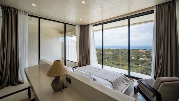 Une chambre d’hôtel moderne dotée d’une grande fenêtre offrant une vue panoramique sur le paysage.