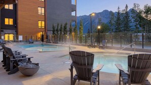 A pool area with lounge chairs and a view of mountains. - Hidden Cirque Hydeaway at Ascent (Canmore)