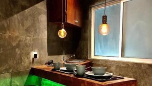 A compact kitchen with a wooden island, two stools, and pendant lighting. - zyan Rooms (Villahermosa)