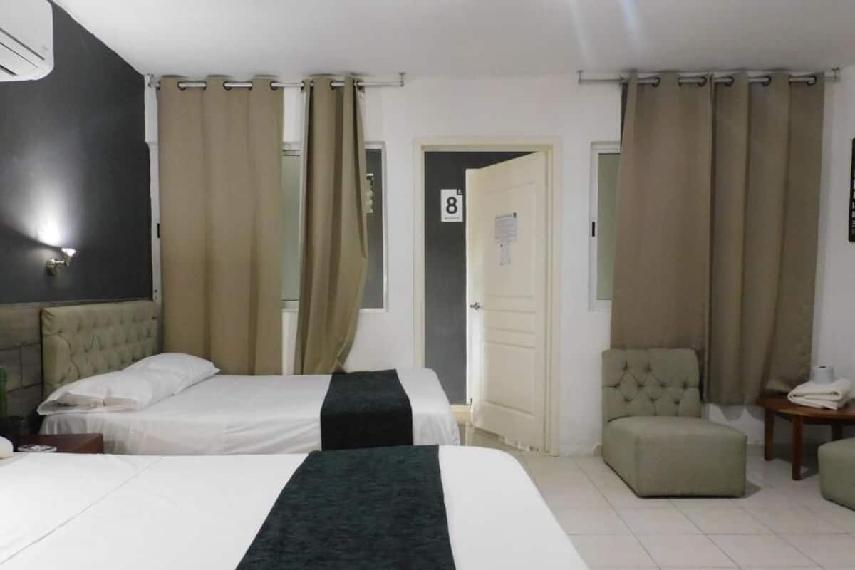 Ein Hotelzimmer mit zwei Betten, einer kleinen Sitzecke und einer Tür mit der Nummer 8.