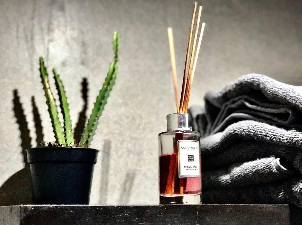 A potted plant, a bottle of cologne, and a folded towel on a shelf.