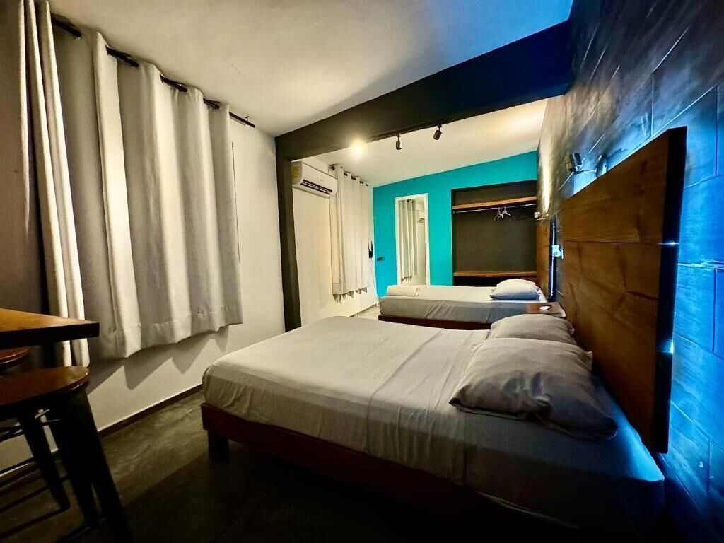 Habitación de hotel con dos camas, cabecero de madera, un escritorio y una ventana con cortinas.