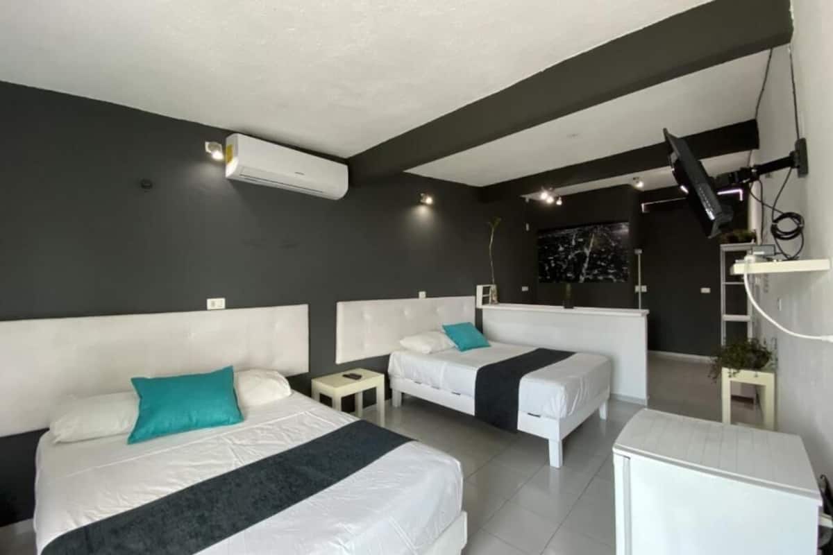 Ein modernes Hotelzimmer mit zwei Betten, einem Schreibtisch, einem Stuhl und einem an der Wand befestigten Fernseher.