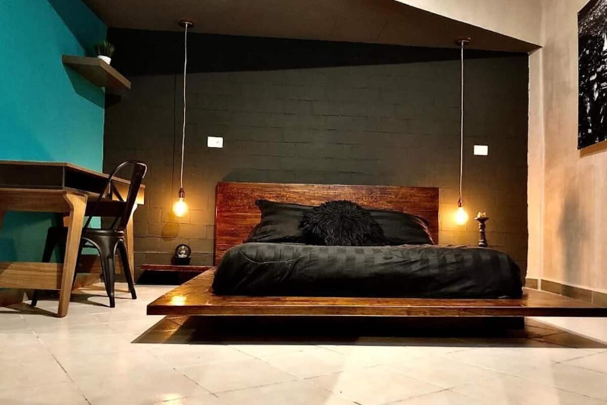 Ein modernes Schlafzimmer mit einem niedrigen Plattformbett, einem Holzkopfende und Pendelleuchten.