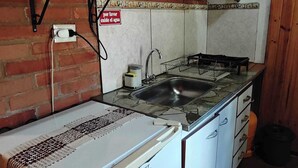 Eine kleine Küche mit Kühlschrank, Mikrowelle, Spüle und Durchlauferhitzer.