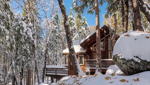 A wooden cabin surrounded by snow-covered trees.