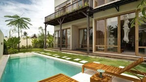 A modern house with a swimming pool, wooden deck, and a balcony with plants. - KOO villa (Pejeng Kawan)
