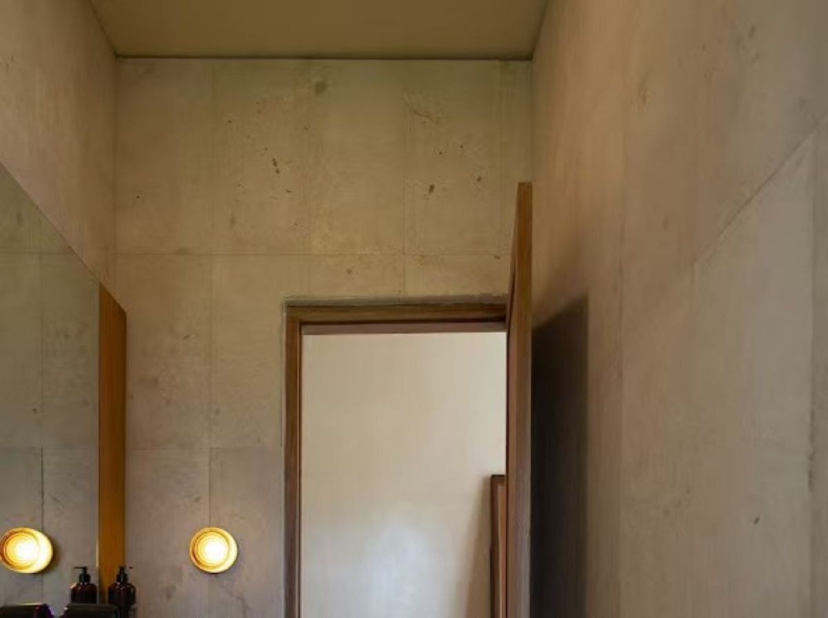 A bathroom with a large mirror, two wall-mounted lights, and a wooden door.