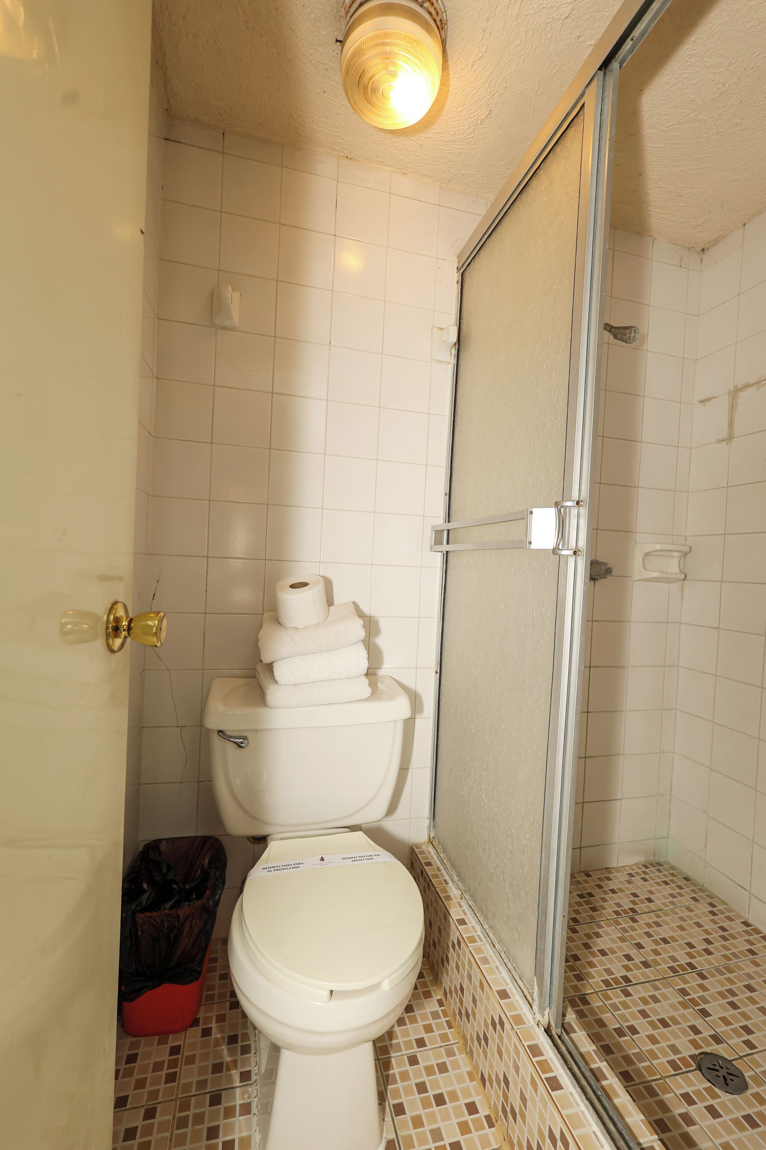 A bathroom with a toilet, a shower enclosure, and a tiled floor.
