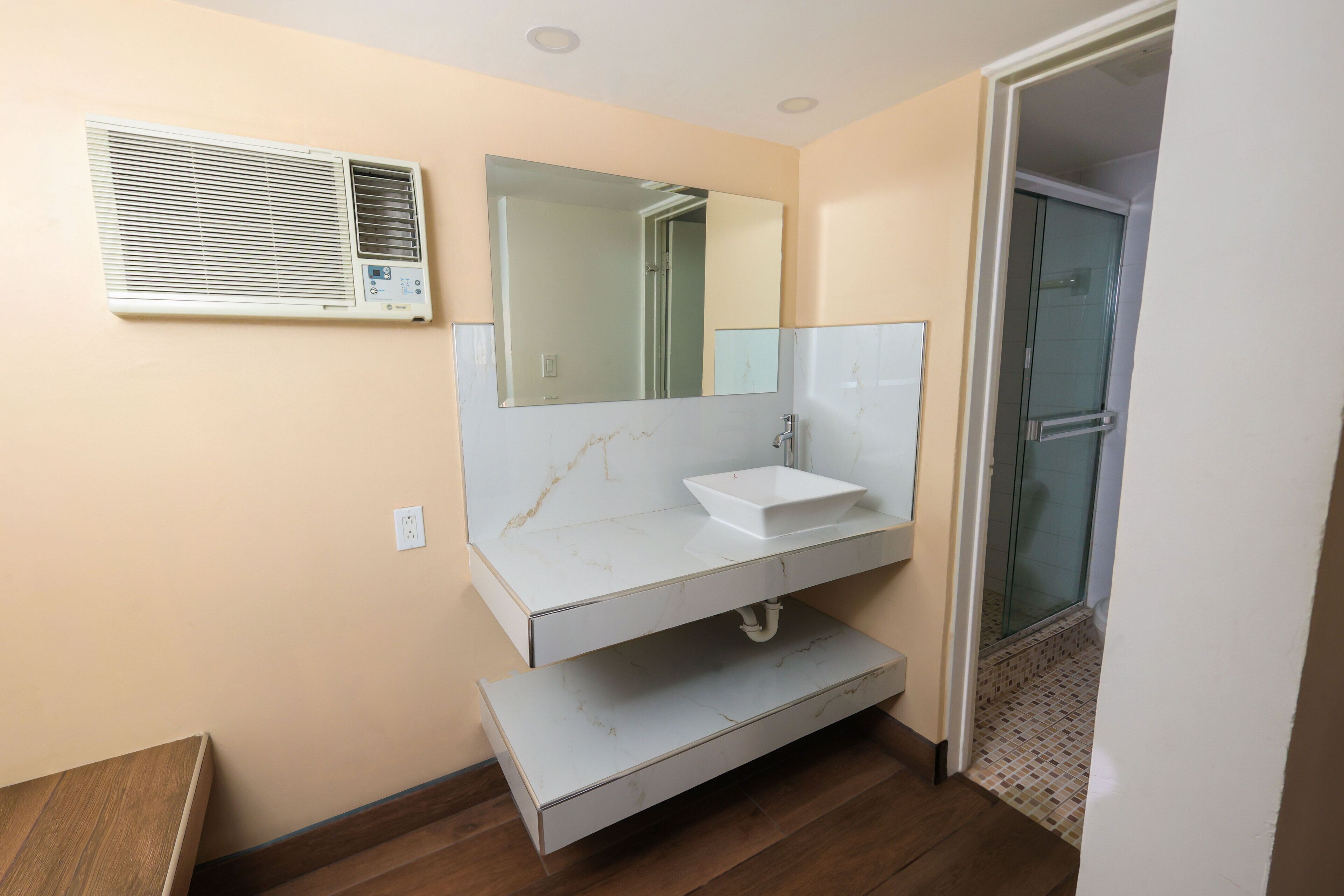 A bathroom with a white sink, a large mirror, and a shower with a glass door.