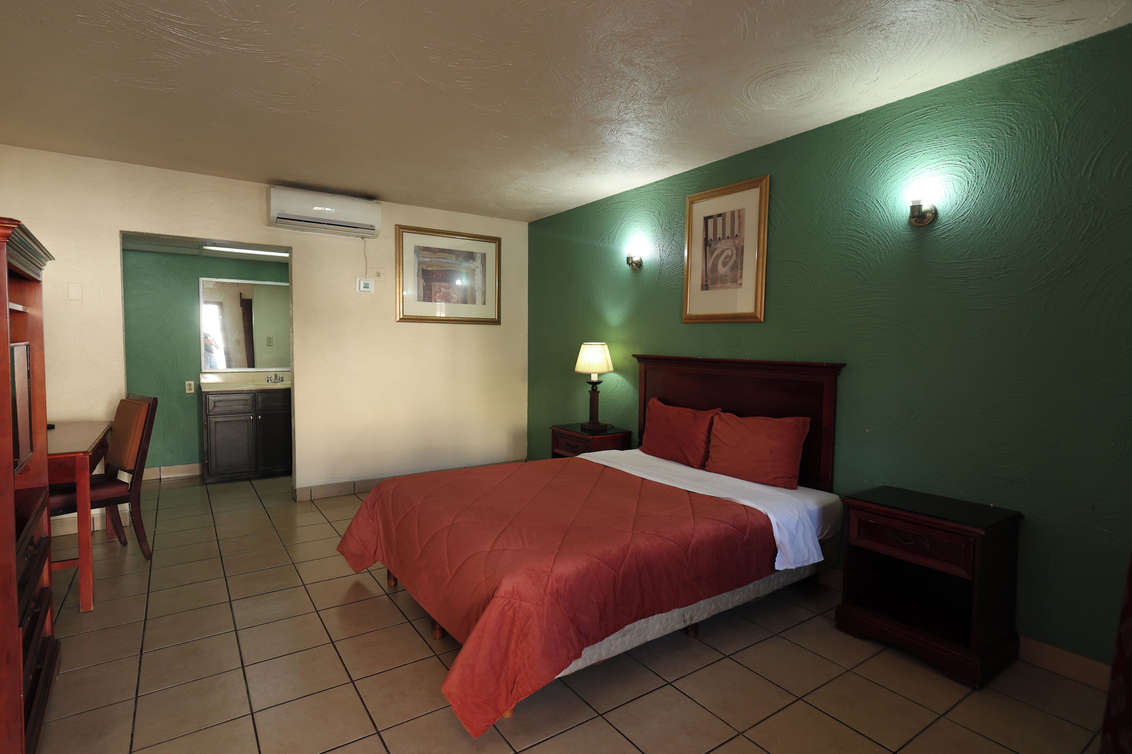 Ein Hotelzimmer mit einem Bett, Nachttischen, einem Schreibtisch und einem Sessel.