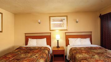 Una camera d'albergo con due letti, un comodino con una lampada e un quadro appeso alla parete.