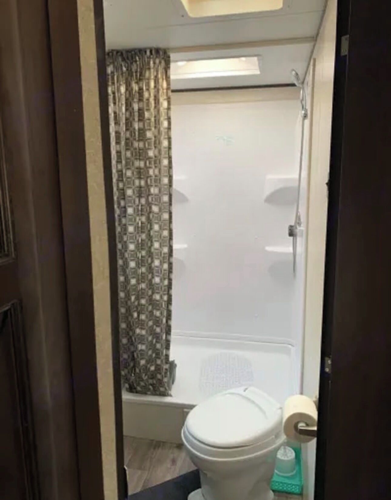 Ein kleines Badezimmer mit Toilette, einer Duschvorhang und einem Oberlicht.