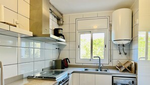 A modern kitchen with white cabinets, a stainless steel stove, a Bosch dishwasher, and a window providing natural light. - BARCA.Apartment with direct Beach Access (ROSES)