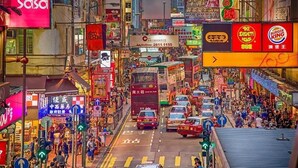 Una vivace strada cittadina con diversi cartelli pubblicitari e insegne commerciali, tra cui un'insegna 'Burger King' ben visibile.