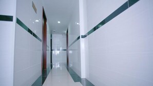 Un corridoio con pareti bianche e tocchi di verde, che conduce a una porta in fondo.