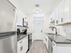 A compact kitchen with white cabinets, stainless steel appliances, and a tiled backsplash. - Vistas-In Old Town-Walk to Entertainment District (Scottsdale)
