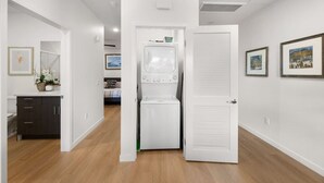 A laundry room with a washer and dryer, a small cabinet, and framed pictures on the wall. - Lux Beach Retreat: Parking/Wifi (San Diego)