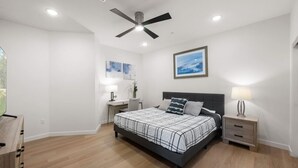 A bedroom with a bed, bedside tables, a ceiling fan, and artwork on the wall. - Lux Beach Retreat: Parking/Wifi (San Diego)