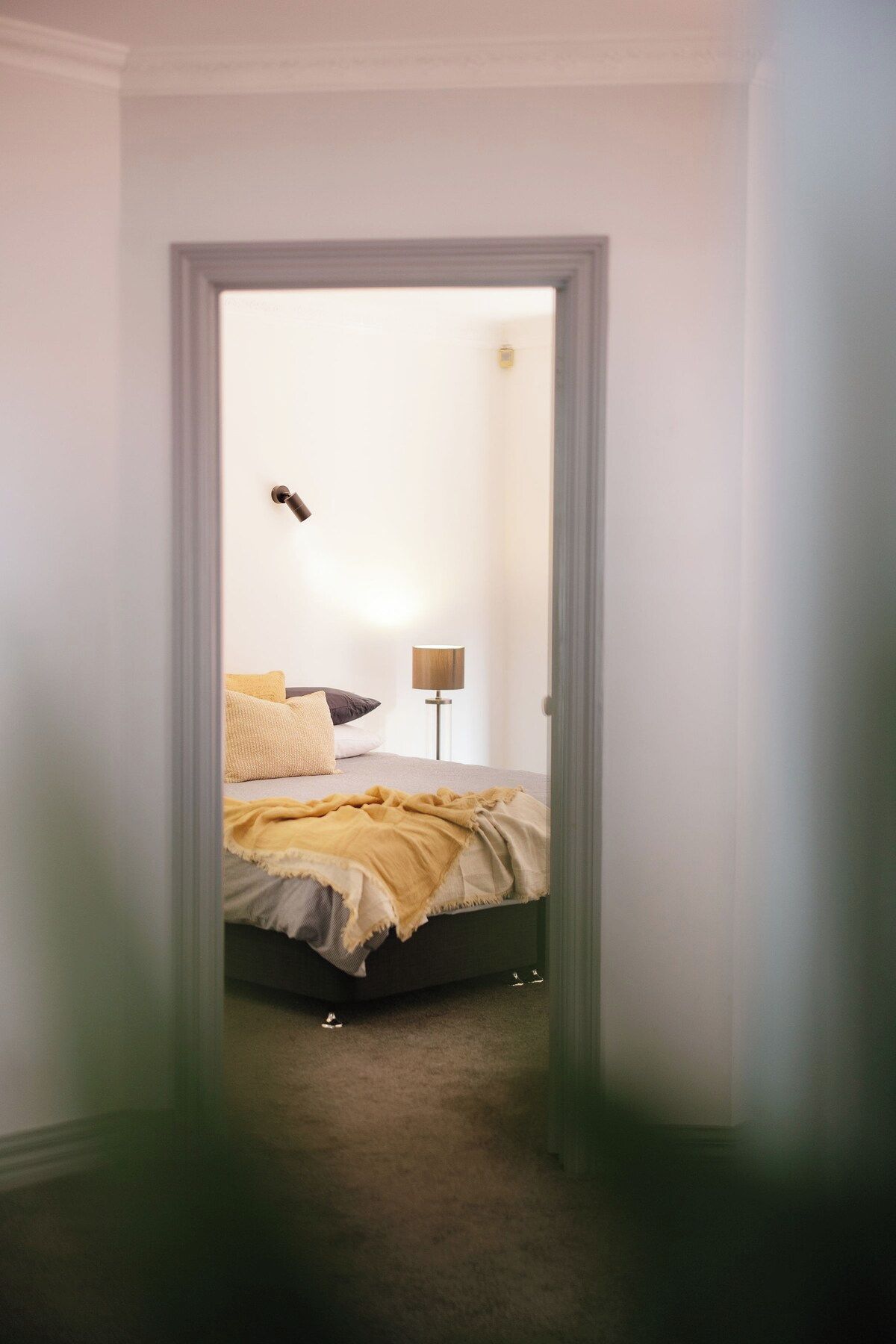 A bedroom with a bed, pillows, a lamp, and a door.