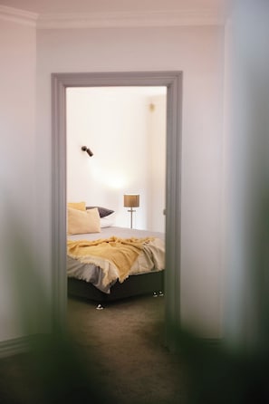 A bedroom with a bed, pillows, a lamp, and a door.