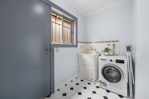 A compact laundry room with a washing machine, a dryer, and a small cabinet. - The Laneway | 3BR - Families & Crews · Walk To CBD (Port Lincoln)