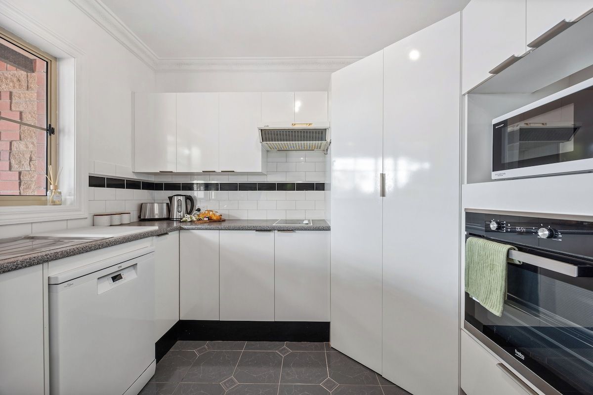 A modern kitchen with white cabinets, a built-in oven, and a dishwasher.