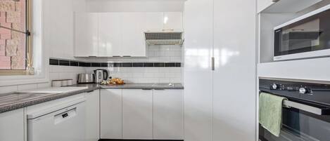 A modern kitchen with white cabinets, a built-in oven, and a dishwasher.
