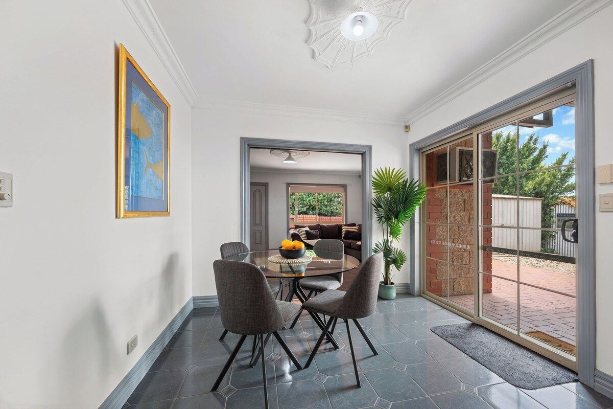 Un coin repas avec une table et des chaises en verre, une plante en pot et une vue à travers une porte vitrée.