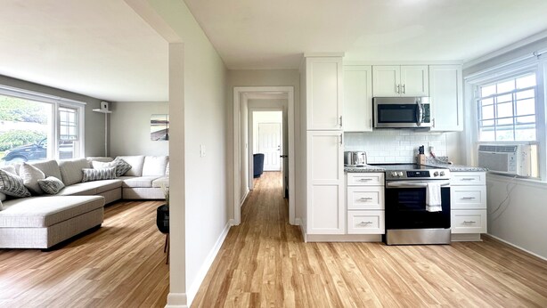 Una cocina moderna con armarios blancos, estufa de acero inoxidable y microondas.