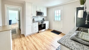 Una cocina moderna con armarios blancos, microondas, horno y refrigerador.