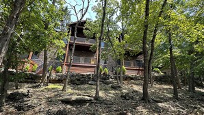 Une cabane rustique avec des fondations en pierre, un revêtement extérieur en bois et un balcon.