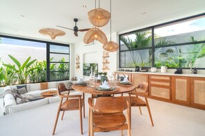 A modern dining area with a round wooden table, wicker pendant lights, and a ceiling fan. - Villa Sofra 2BR Private Pool, 350mbps WiFi- Bingin (South Kuta)