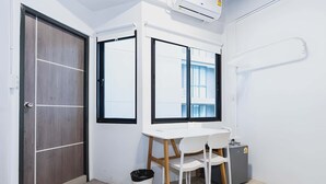 Une petite pièce propre, avec un bureau blanc, deux chaises, une poubelle et une fenêtre.