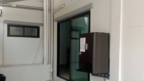 Une pièce propre, de style industriel, avec un sol carrelé, une grande fenêtre et une boîte électrique fixée au mur.
