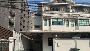 Un bâtiment à deux étages doté d’une entrée abritée et d’une allée menant à une porte.