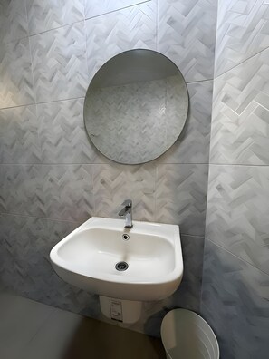 A bathroom with a white sink, a round mirror, and a toilet. - Yellow Place Sukhumvit Soi 2 (Bangkok)
