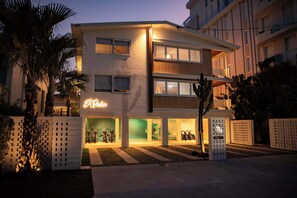 A modern hotel with a neon sign, multiple floors, and a well-lit entrance. - Spacious Bilinga Beach Stay | Sleeps 6 + Sauna, Unit 5 (Bilinga)