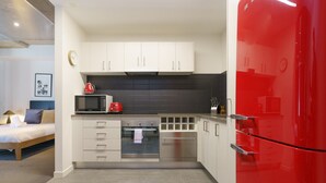 A compact kitchen with white cabinets, a red refrigerator, a microwave, and a coffee maker. - Spacious Studio in a Prime Braddon Location (Braddon)