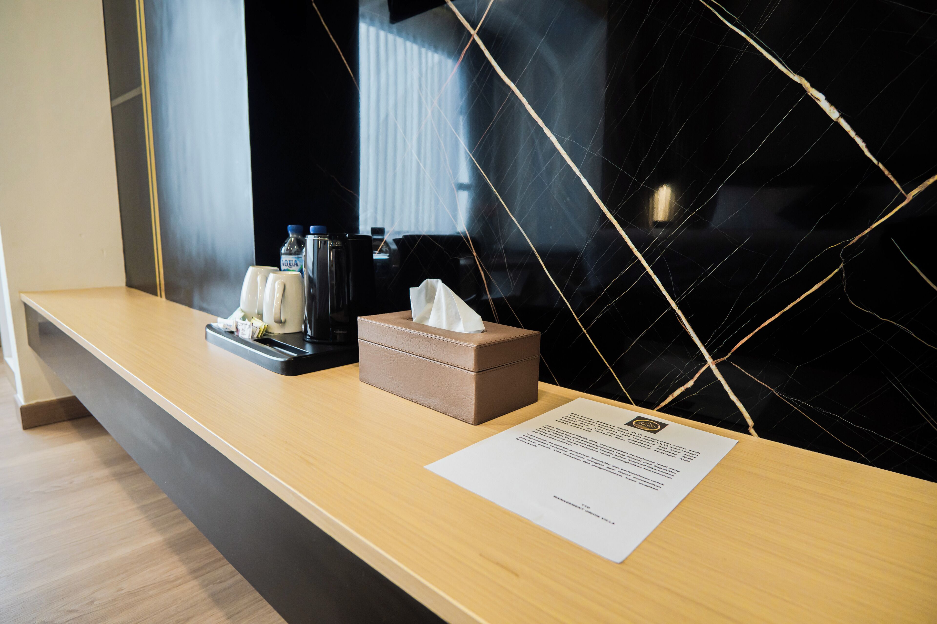 A hotel reception desk with a tissue box, a water bottle, and a menu.