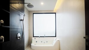 A modern bathroom with a freestanding bathtub, a showerhead, and a large window providing natural light. - Orion Villa Telaga Menjer (Garung)
