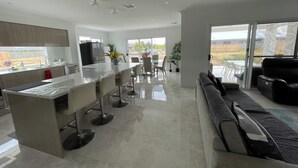 Una cocina moderna con una isla central, taburetes de bar y una zona de comedor con mesa y sillas.