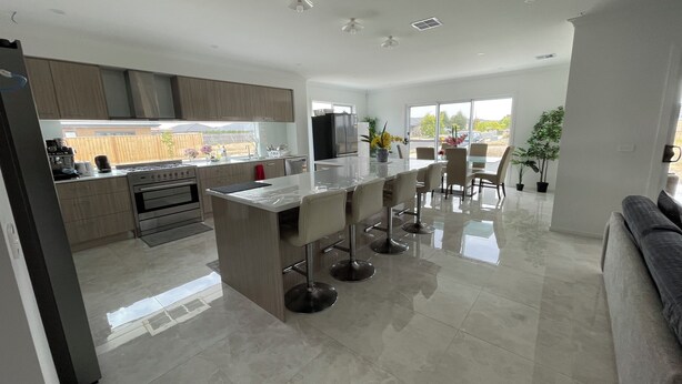 Una cocina moderna con una isla central, un comedor con mesa de vidrio y una sala de estar con sofá.