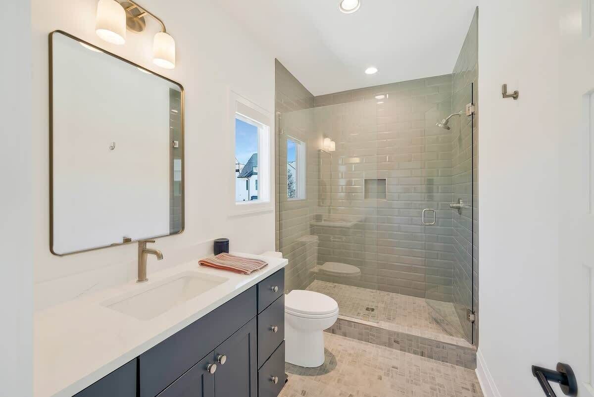 A modern bathroom with a large mirror, a sink, and a glass-enclosed shower.