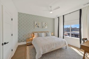 Ein Schlafzimmer mit Bett, Nachttisch, Fenster mit Blick und Deckenventilator.
