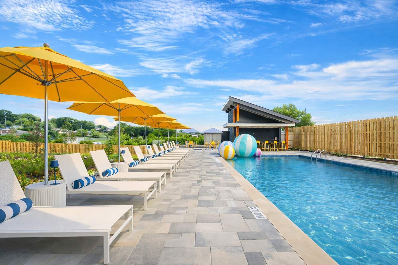 A poolside area with lounge chairs, umbrellas, and a pool.