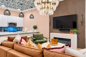 Ein modernes Wohnzimmer mit Sofa, Fernseher, Kamin und einer Küchenzeile mit Mikrowelle.